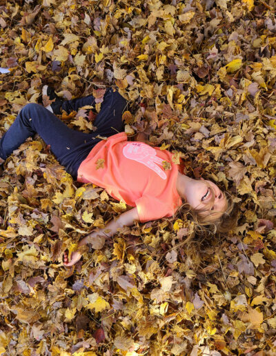 little girl playing in the leaves outside